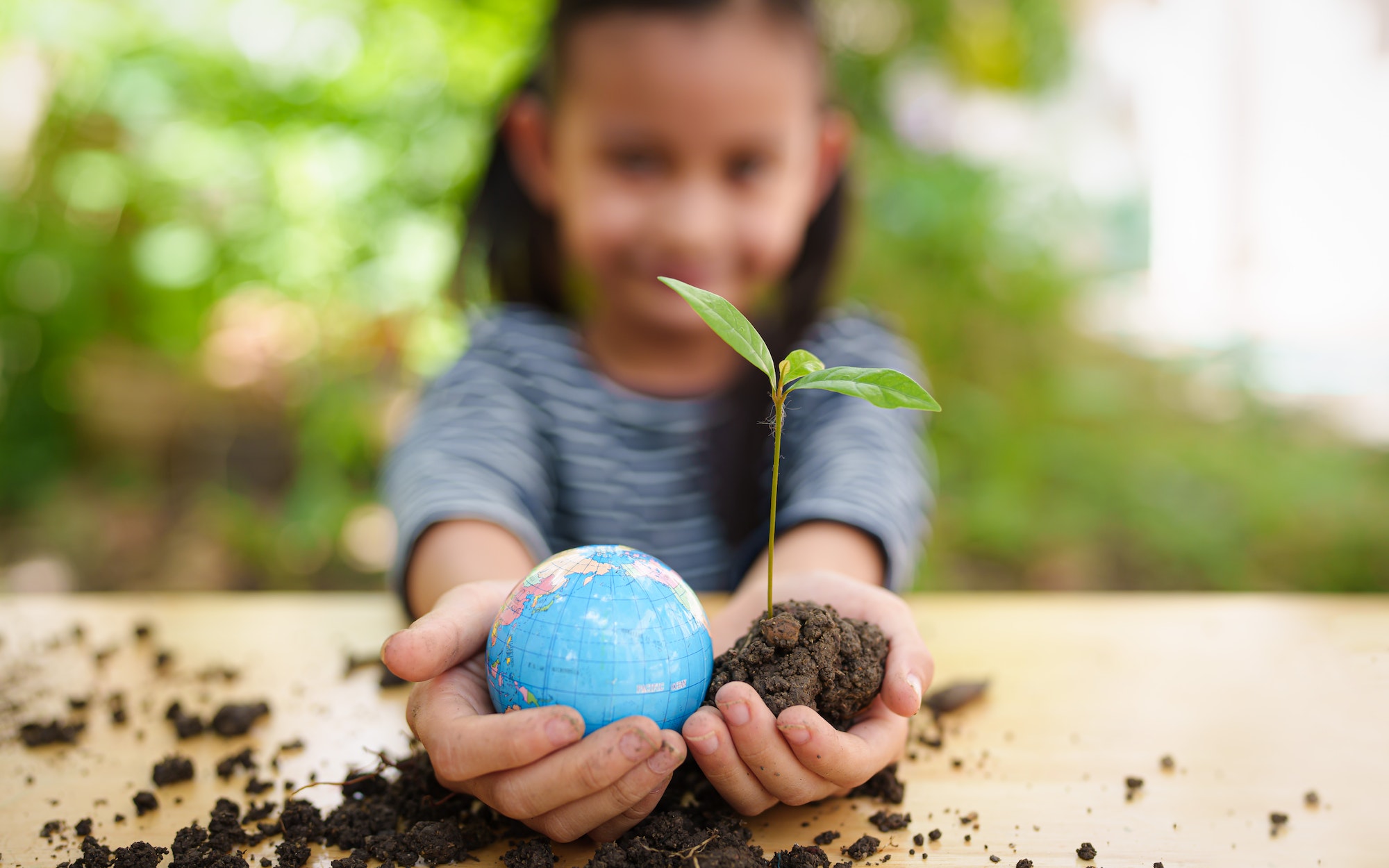 Blurred of little girl is holding plant and globe model together, concept of ESG, environment.